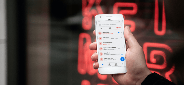 person holding white phone in front of neon sign